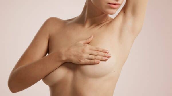 Closeup cropped portrait young woman with breast pain touching chest colored isolated on background